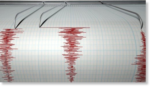 A closeup of a seismograph machine needle drawing a red line on graph paper depicting seismic and eartquake activity 