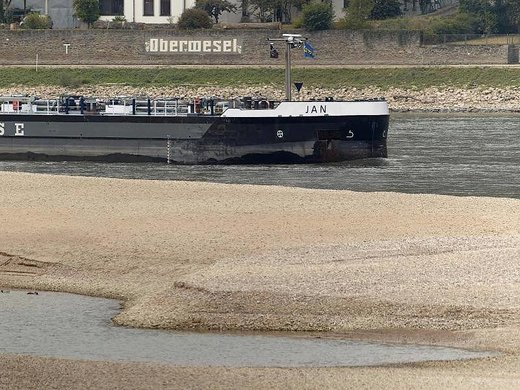 Ein Frachtschiff passiert bei Niedrigwasser eine Sandbank auf dem Rhein.