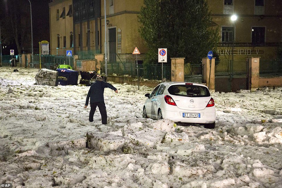 A man tries to reach a car that has been blocked by ice after a severe hailstorm hit Rome, Italy, on Sunday evening