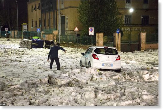 A man tries to reach a car that has been blocked by ice after a severe hailstorm hit Rome, Italy, on Sunday evening