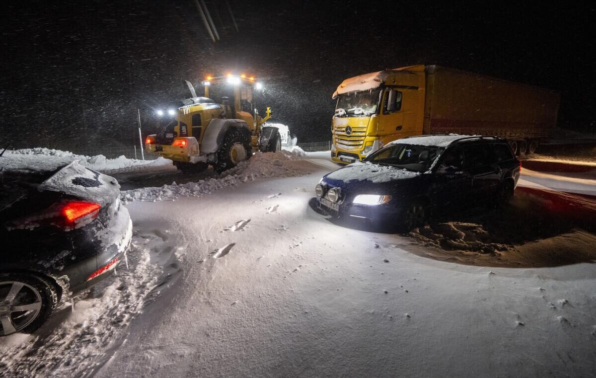 Snow is cleared with wheel loaders as cars and trucks are recovered and people are evacuated with the Home Guard’s tracked vehicle at Ekeröd on the E22 between Hörby and Kristianstad in southern Sweden, Thursday, Jan. 4,