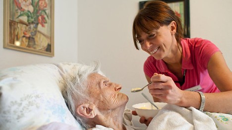 Pflegerin füttert Seniorin